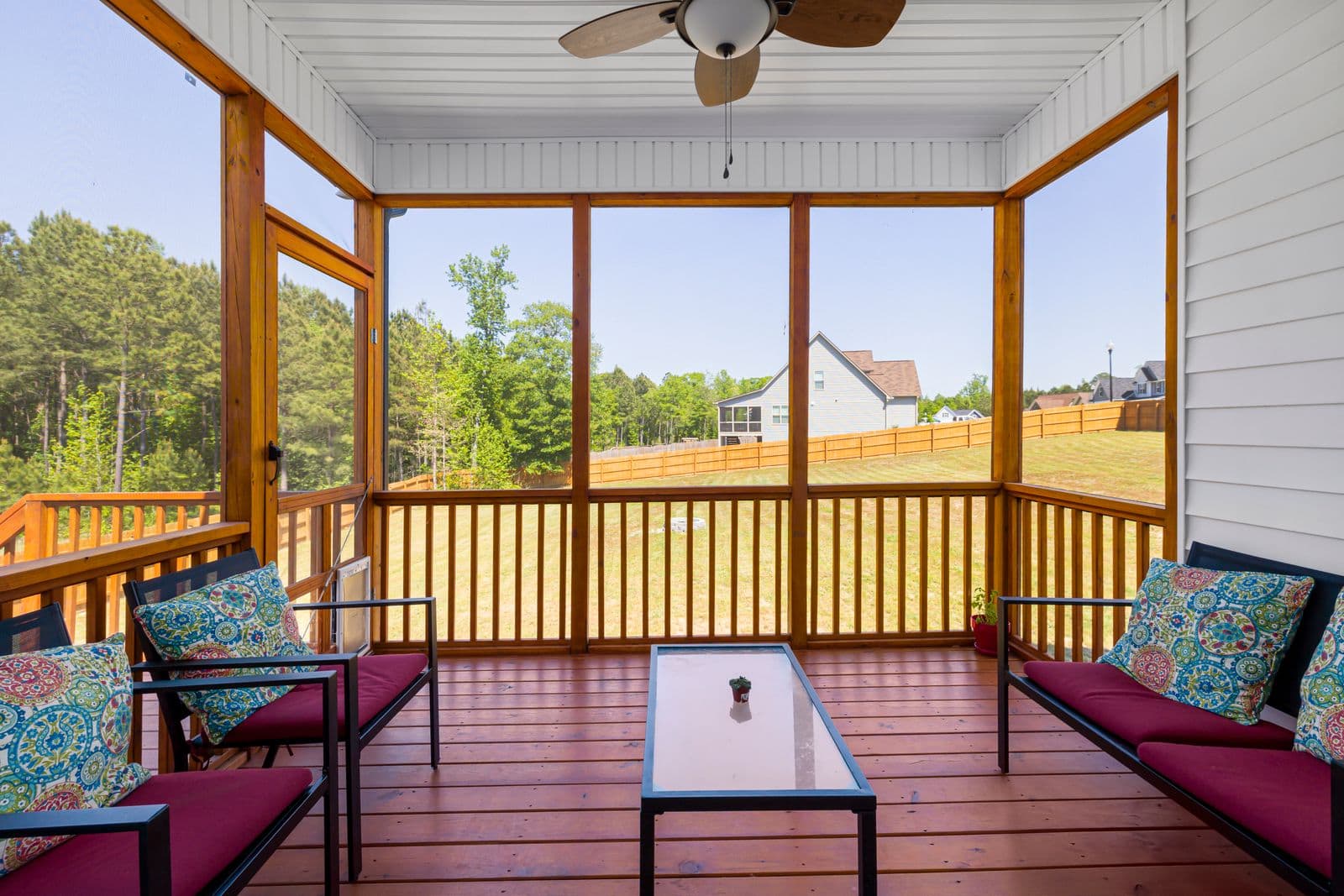 Screened porch with cushioned seating and a view of a green yard